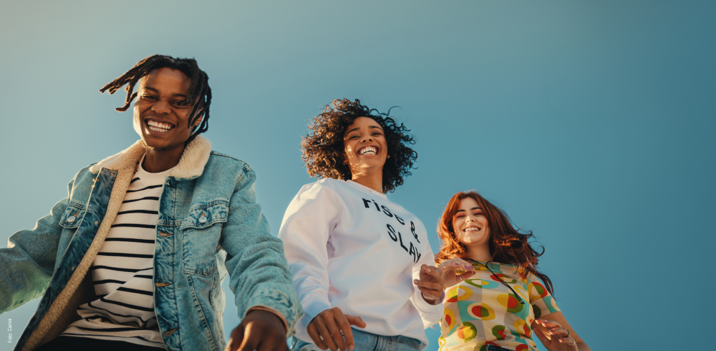 Drei junge Personen lächeln vor einem blauen HIntergrund.